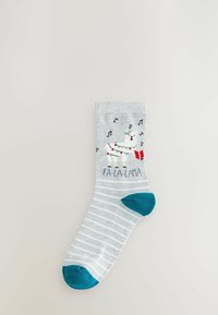 Light gray socks with white stripes feature a graphic of a llama wearing a garland and holding a gift, with the text "FA-LA-LAMA" below.
