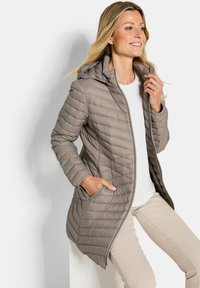 Lichte, gewatteerde beige pufferjack met een capuchon, zijzakken en een ritssluiting aan de voorkant. Glad, zacht materiaal met ribbelstructuren.
