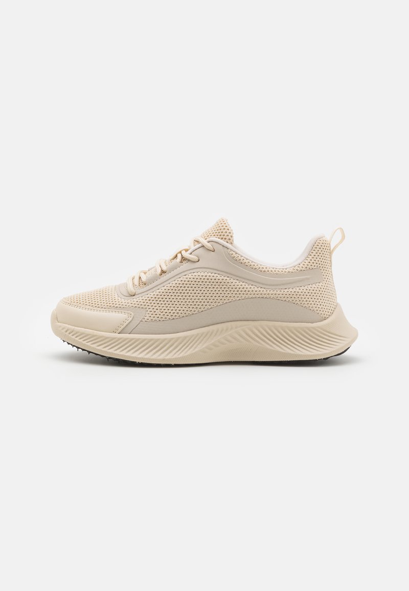 Beige sportieve schoen met bovenwerk van mesh, synthetische accenten, lichtgewicht zool en gestructureerde details. Slank, gestroomlijnd ontwerp met veters.