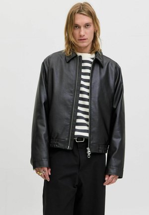 Zwarte leren jas met een kraag, ritsluiting en elastische zoom. Draag over een wit en zwart gestreept sweater.