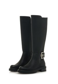 Botas de goma negras hasta la rodilla con acabado brillante, un zipper lateral y una hebilla decorativa plateada en el tobillo exterior. Suela texturizada para mayor agarre.