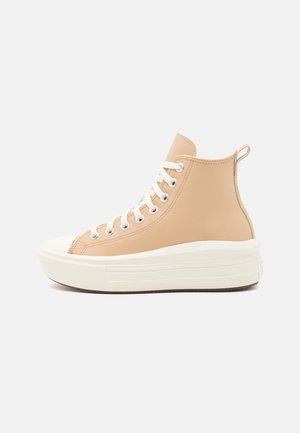 Zapatillas altas beige de cuero con un acabado texturizado, cordones blancos y una suela de goma gruesa de color crema.
