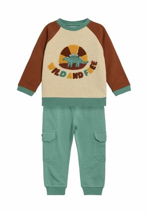 Brown and cream long-sleeve shirt with dinosaur design and "WILD AND FREE" text, paired with mint green cargo pants, soft cotton material.