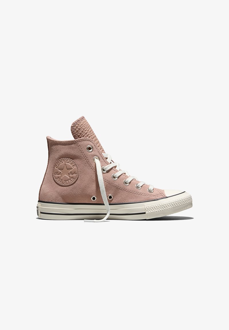 Baskets montantes Converse en daim rose avec lacets blancs, semelle en caoutchouc et logo embossé sur le côté, présentées de profil sur un fond blanc.