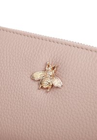Clutch in pelle rosa pallido con finitura testurizzata, accentuato da un'ornamentazione a forma di ape dorata sul davanti. Chiusura con cerniera visibile.
