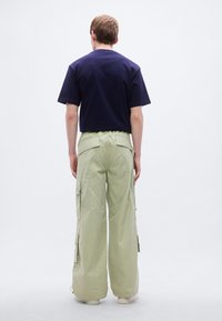 Μπλε ναυτικό βαμβακερό μπλουζάκι συνδυασμένο με ανοιχτοπράσινο παντελόνι cargo με μεγάλες πλαϊνές τσέπες και ελαστική μέση, με άνετη εφαρμογή.