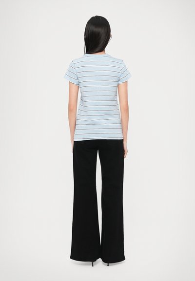 Svetlomodré pruhované tričko s krátkymi rukávmi v kombinácii s čiernymi širokými nohavicami. Tričko má horizontálne pruhy v tmavších farbách.