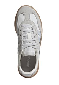 Zapatillas gris claro con detalles en cuero blanco y gamuza gris, que cuentan con una plantilla texturizada en gris y una suela de goma beige.