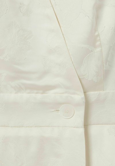 Blazer en tissu blanc avec un motif floral texturé, une fermeture à un bouton et une finition en satin lisse avec un éclat subtil.
