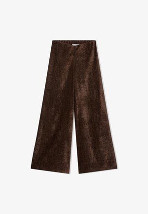 Pantaloni larghi in velluto marrone con vita alta e tessuto morbido e liscio disposti su uno sfondo bianco.