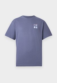 Camiseta de manga corta púrpura con cuello redondo, con texto pequeño en blanco y rojo y caracteres asiáticos en la parte superior izquierda del pecho.