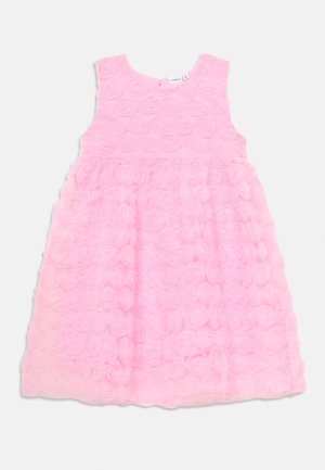 Ružičasta haljina bez rukava, sa slojem teksture cvjetnih aplikacija. Tkanina izgleda mekano i ima lagan, prozračan izgled.