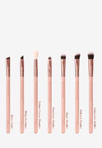 Set di sette pennelli da trucco con manici rosa e ghiera in oro rosa. Presentano diverse forme per precisione, sfumatura e applicazione.