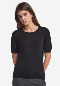 Sort kortærmet strikket top med rund halsudskæring og ribbet kant. Glat tekstur, afslappet pasform og minimalistiske designdetaljer.