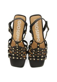 Sandalias negras con tiras, adornadas con remaches en forma de pirámide dorados, con puntera cuadrada y correa ajustable, sobre una suela interior texturizada.