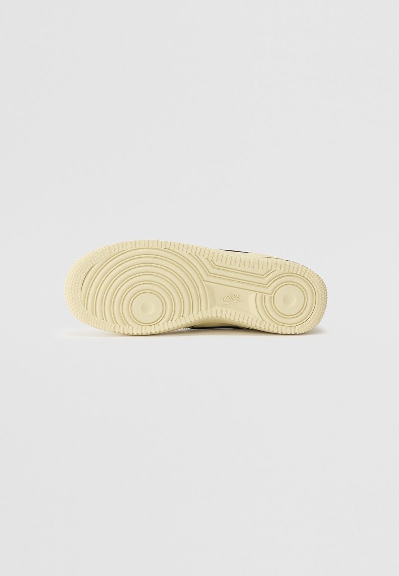 Czarna podeszwa sportowa z teksturowaną, kremową gumową podeszwą zewnętrzną, która ma okrągłe wzory i wypukłe akcenty w okolicy pięty i łuku.