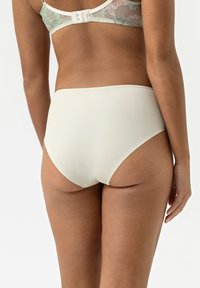 Hoge taille crèmekleurige slipjes, gemaakt van gladde stof met een lichte glans, met een naadloos ontwerp en een elastische tailleband voor comfort.