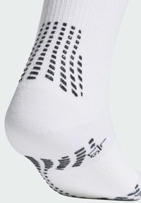 Calcetín deportivo blanco con empuñaduras negras texturizadas en la parte inferior. La tela es ligera y elástica, diseñada para un ajuste y comodidad óptimos.