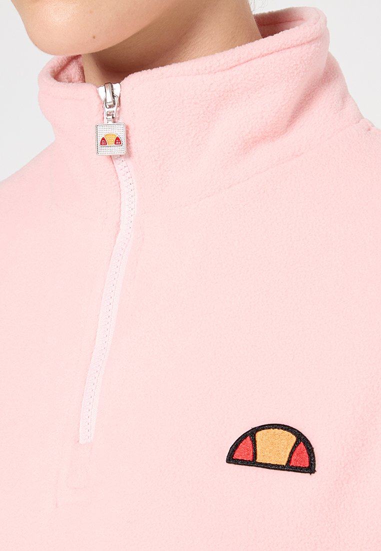Pull en polaire rose doux, doté d'un col zippé et d'un petit logo multicolore sur la poitrine gauche. Texture lisse et design moderne.