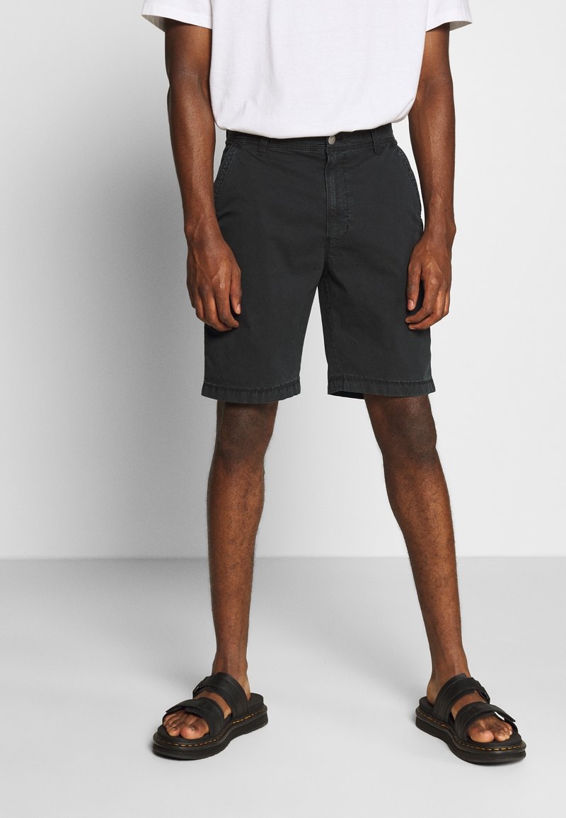 Černé bavlněné šortky s rovnými nohavicemi, předními kapsami a zapínáním na jeden knoflík, spárované s černými sandály s širokými popruhy.