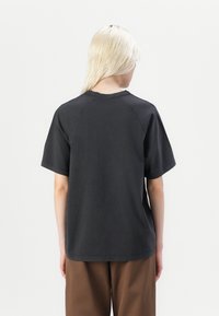 T-shirt en coton gris foncé à manches courtes, avec un col rond et une coupe décontractée. Texture lisse sans motifs ou ornements notables.