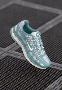 Nakitno zeleni Nike tenisice s mrežastom gornjom površinom, uzorcima na preklopima i bijelim naglascima. Imaju udoban potplat i sustav vezivanja.