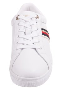 Białe syntetyczne sneakersy z okrągłym noskiem, sznurowanym przodem oraz ozdobnym paskiem w kolorze czerwonym, czarnym i beżowym po boku. Teksturowana gumowa podeszwa.