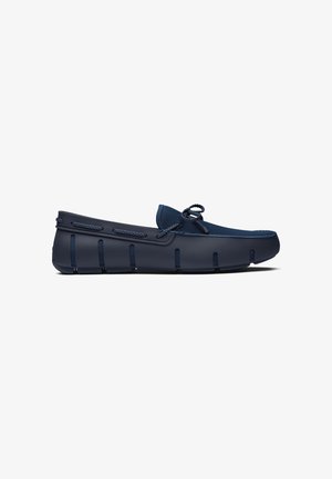 Marineblauwe instap loafer met mesh bovenwerk, gevlochten veterdetail en rubberen zool met verticale groeven voor grip en flexibiliteit.