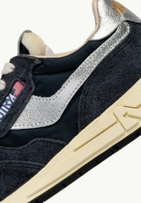 Sneaker nero e argento con suede testurizzato, striscia laterale metallica, suola beige e dettaglio della bandiera americana sulla linguetta.