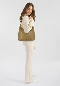 Borsa hobo in pelle marrone con un texture liscia, una tracolla singola e un design minimalista. Esposta su uno sfondo neutro.