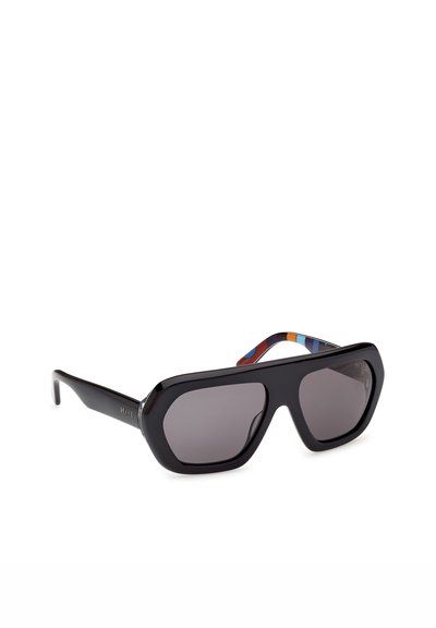 Gafas de sol rectangulares negras de gran tamaño con lentes oscuras y varillas interiores a rayas multicolores, colocadas en ángulo sobre un fondo blanco.