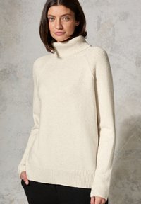 Cremfarbener Rollkragenpullover mit gerippten Akzenten an Ärmeln und Saum. Weiche Textur, lässiger Schnitt, geeignet für Freizeitbekleidung.
