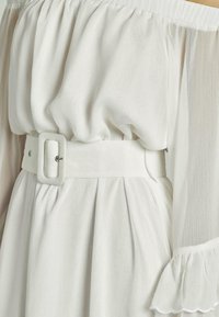 Weißes schulterfreies Kleid mit plissiertem Rock, Stoff mit weicher Textur und einem passenden Gürtel mit rechteckiger Schnalle.