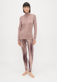 Pikad varrukad, kõrge kaelusega topp ja sellele sobivad retuusid helesinises roosa värvitoonis abstraktse mustriga, valmistatud pehmest ja venivast kangast.