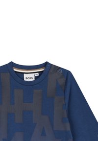 Marineblauwe sweatshirt met een groot grijs logo in een textuur. Heeft een ronde hals en drukknoopsluitingen op de schouder voor gemakkelijke aan- en uitkleding.