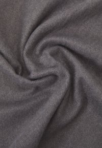 Tissu gris avec une surface douce et texturée, présentant un motif subtil et un drapé lisse et fluide, suggérant chaleur et confort.