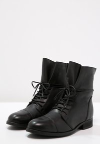 Black leather ankle boots with a rounded toe, lace-up front, and cuffed top. Features a flat heel and visible stitching accents.