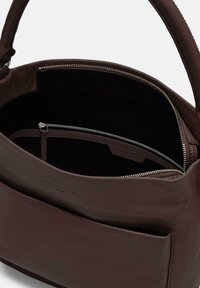 Ciemnobrązowa skórzana torebka o gładkiej fakturze, z zamkiem błyskawicznym i kieszenią wewnętrzną. Posiada prosty, uporządkowany design z krótkim uchwytem.