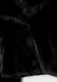 Musta tekoturkiskangas, jossa on pehmeä ja tiheä rakenne. Siinä on pitkät, virtaviivaiset karvat, jotka luovat ylellisen ilmeen, tiheästi kudottu ja väriltään tasainen.