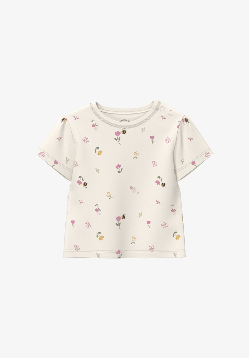 Chemise bébé à manches courtes couleur crème avec petits motifs floraux roses, jaunes et verts ainsi que des abeilles, boutonnée avec des pressions sur une épaule.