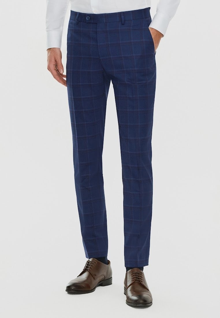 Granatowe w kratę spodnie w kant o dopasowanym kroju, z płaskim przodem, kieszeniami bocznymi, w zestawie z brązowymi skórzanymi butami.