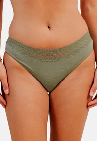 Un bas de bikini vert olive présentant une finition en dentelle festonnée à la taille, une texture lisse et un design à coupe classique.