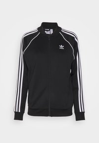 Svart Adidas zip-up jacka med vita ränder på ärmarna och Adidas-logotypen på vänster bröst, visad på en helt vit bakgrund.