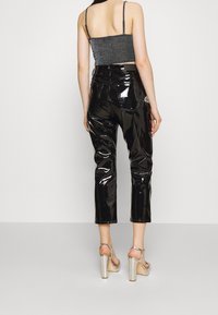 Svarta lackbyxor med hög midja, avkortad längd och glänsande yta; kombinerat med en grå metallisk crop top och silvriga högklackade skor.