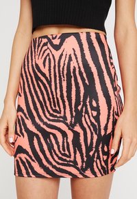 Mini falda en vibrante color rosa con rayas de cebras negras texturizadas, con un ajuste ceñido y tela suave. Sin cierres ni adornos visibles.