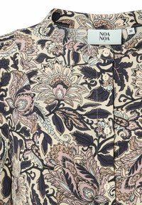 Blommig blus med rund halsringning, knappstängning och en ljus beige bakgrund. Har detaljerade mönster i rosa och mörk marinblått.