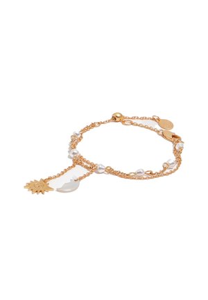 Pulsera delicada de cadena de oro con pequeñas perlas blancas, con encantos de sol y luna colgando de dos hilos.