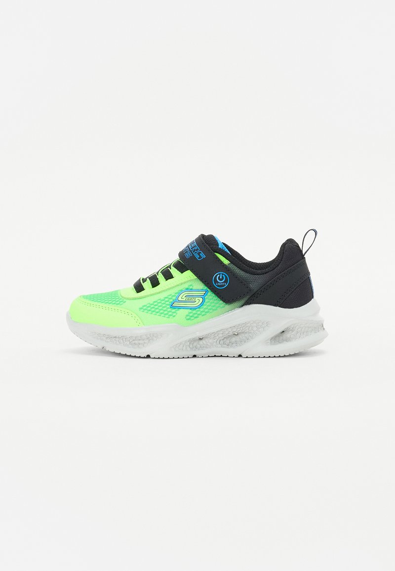 scarpa atletica verde neon e nera con tomaia in mesh, elastici, cinturino regolabile e suola in gomma bianca con dettagli testurizzati.