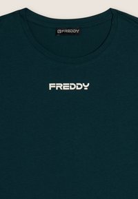 Camiseta de cuello redondo de color verde oscuro con el nombre de la marca "FREDDY" impreso en blanco centrado debajo del cuello.