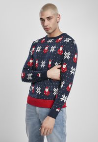 Pulover tricotat de culoare albastru marin cu fulgi de nea albi și modele roșii cu Moș Crăciun. Are un tiv și manșete rigate roșii, realizat dintr-un material texturat și moale.